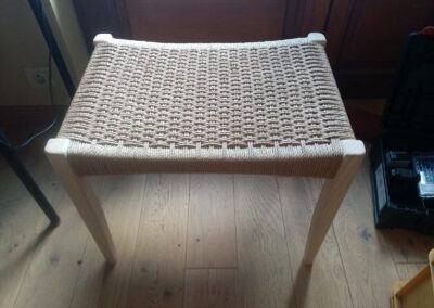 Tabouret en bois clair dont l'assise est tissée en corde danoise écrue